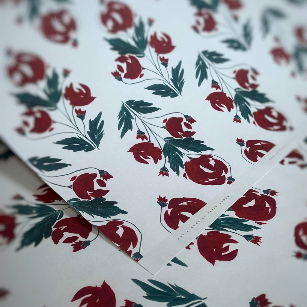 Floral patterned paper with red flowers and green leaves on a white background