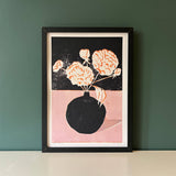 Framed artwork of a vase with flowers on a dark background, displayed against a green wall.