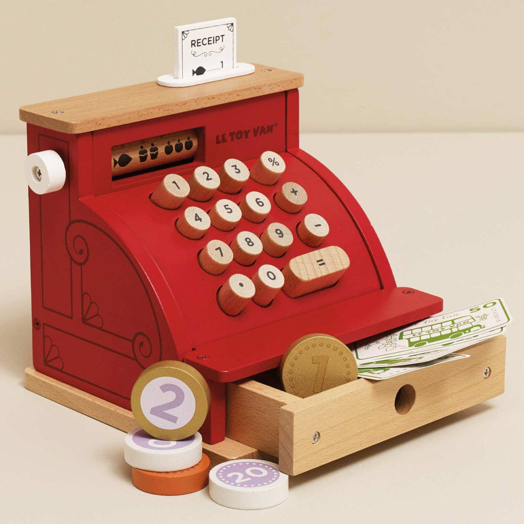 Wooden toy cash register with red display and wooden base on a beige background