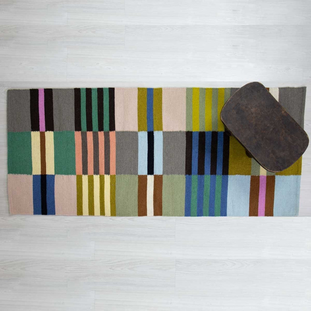 Striped, patterned rug under a wooden footstool