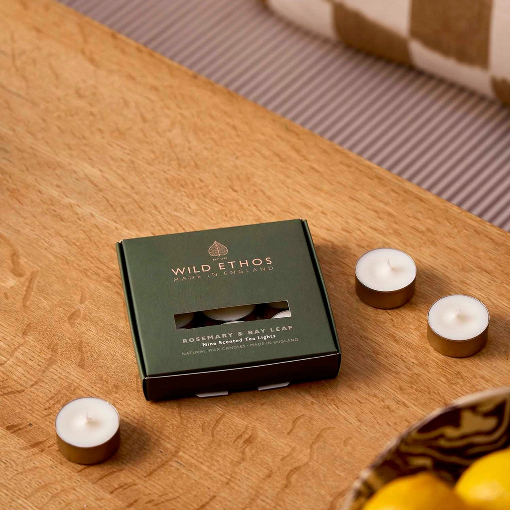 Box of Wild Ethos tea lights on a wooden surface with candles around