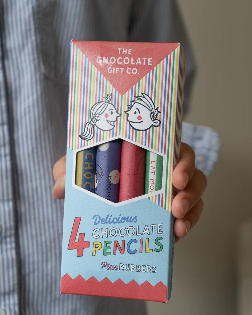 Packaging of chocolate pencils with visible branding held by a person.