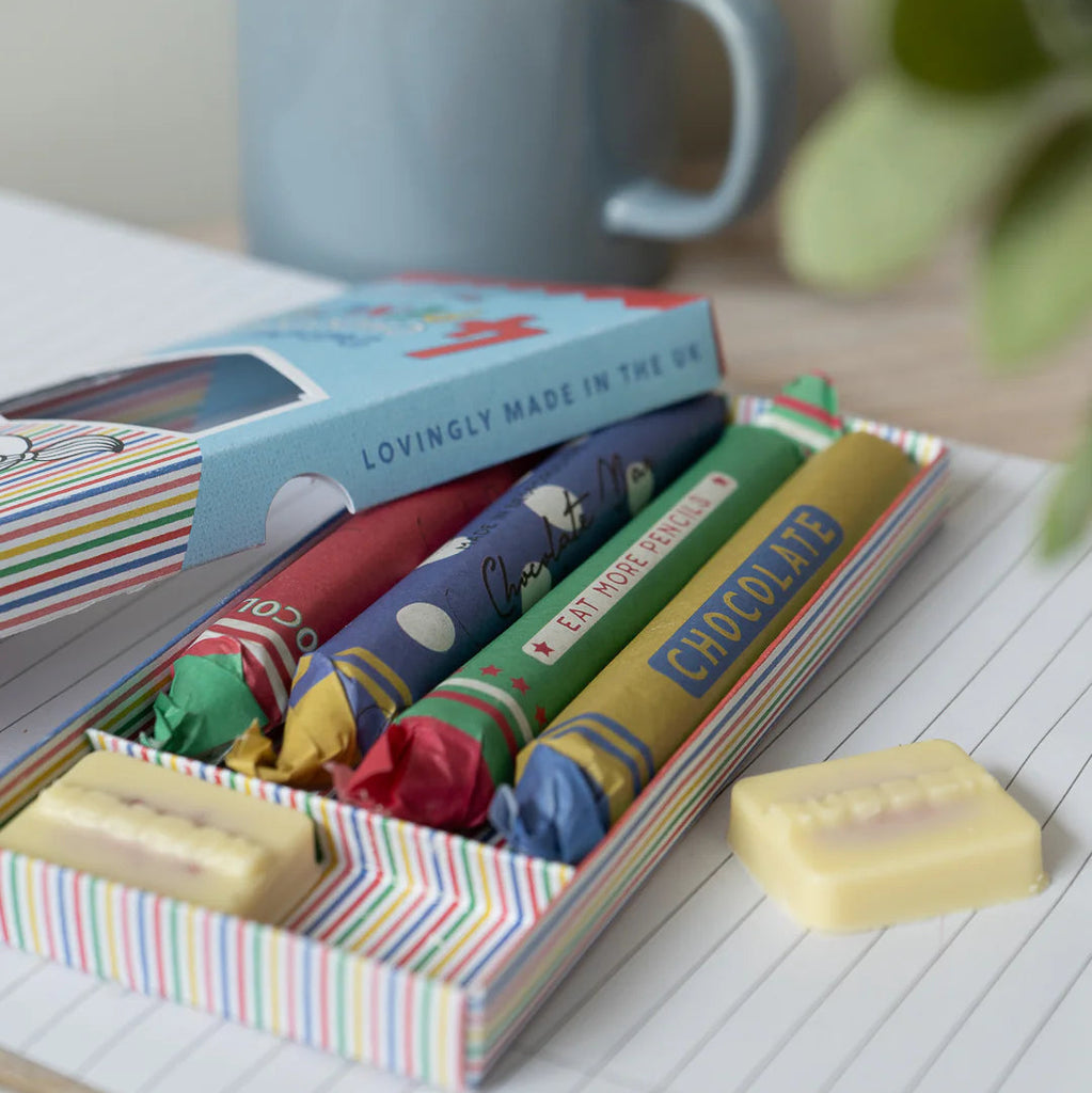 Box of colorful chocolate bars with a mug in the background