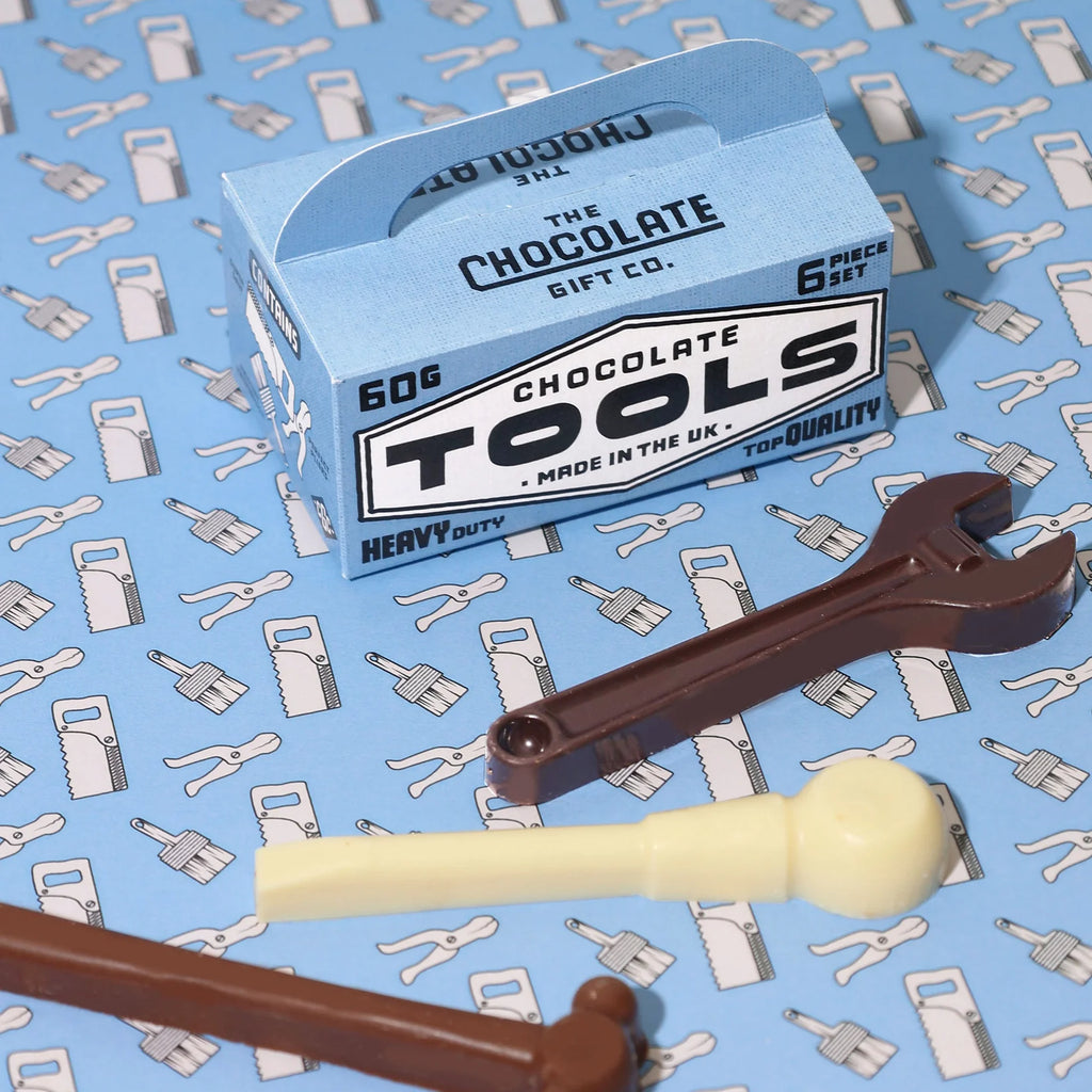 Tool shaped chocolates arranged on a blue printed background with a blue card toolbox