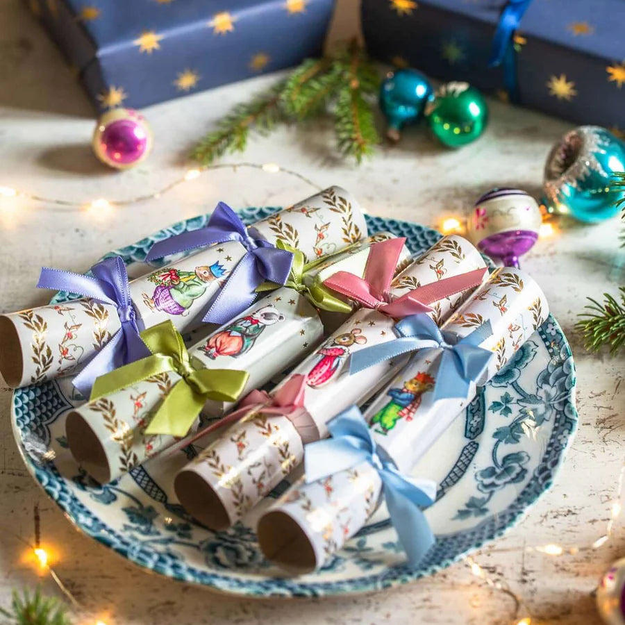 Decorative Christmas crackers on a plate with festive lights and presents in the background