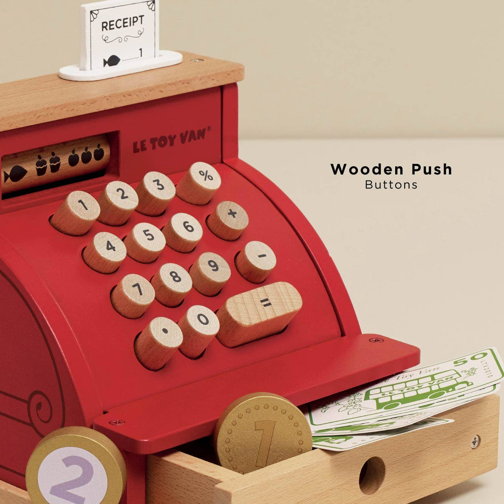 Red toy cash register with wooden push buttons on a beige background