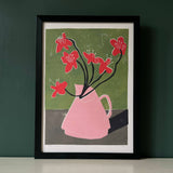 Framed artwork of a pink vase with red flowers on a green background