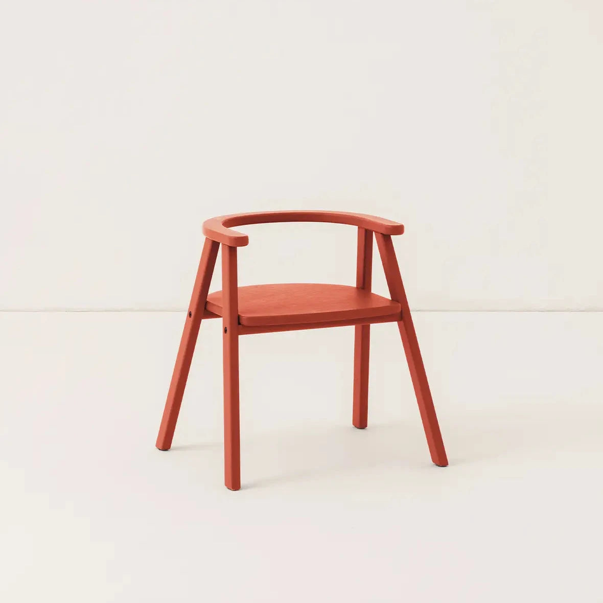 Red wooden kids chair, against a cream background