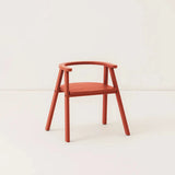 Red wooden kids chair, against a cream background