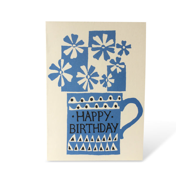 A screen printed design, of a blue mug with blue and white flowers on a cream background with a 'Happy Birthday' message. Designed by Cambridge Imprint.