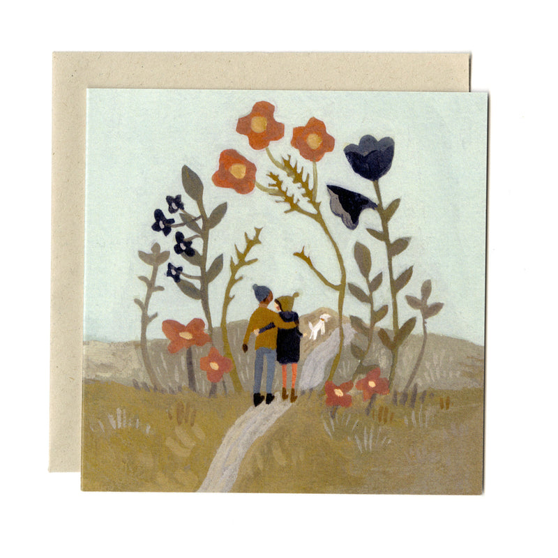 A square card by artist Gemma Koomen, featuring a gouache illustration of two figures walking along a path, surrounded by flowers. Shown with accompanying cream envelope.